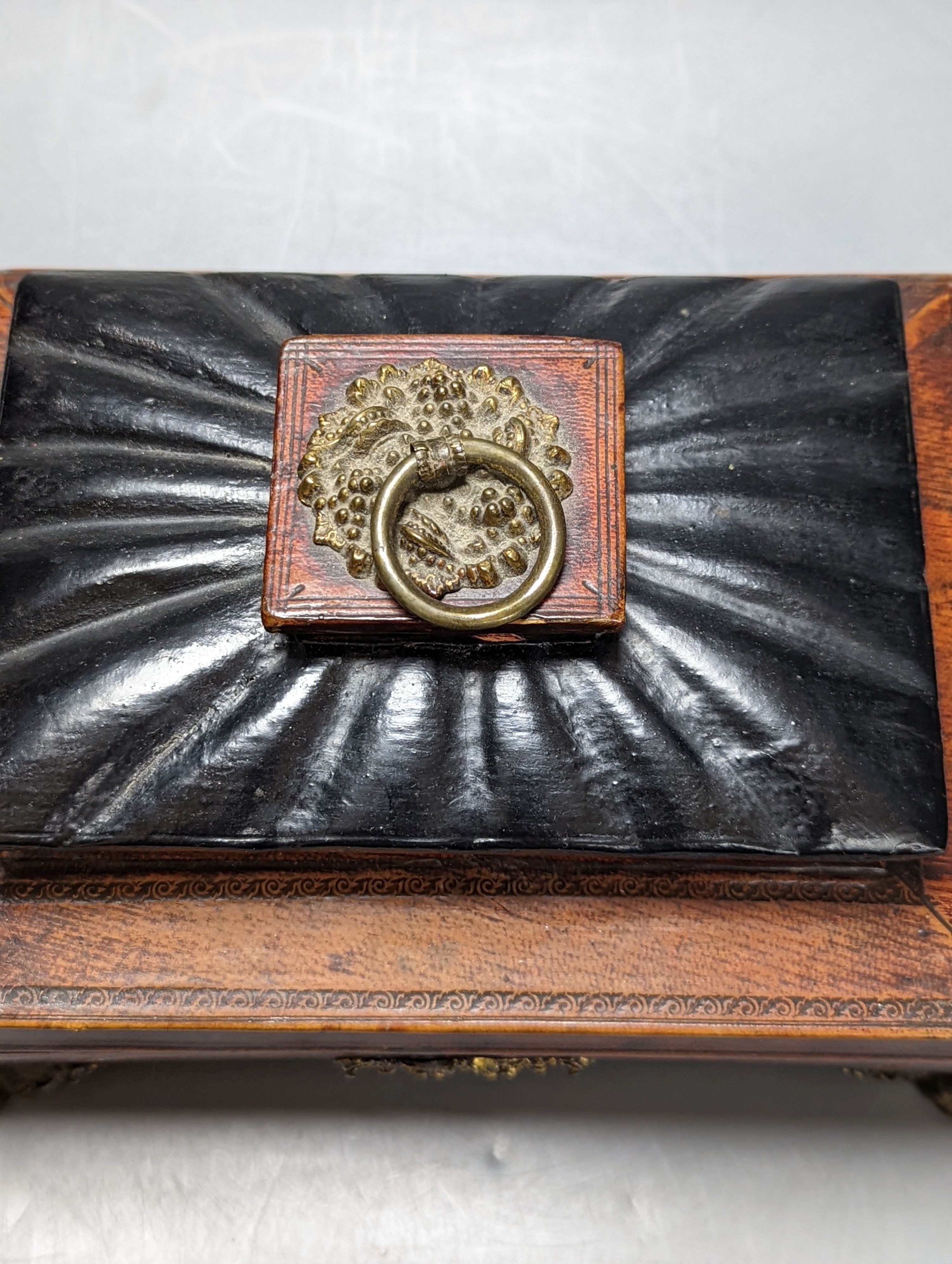 A George IV tooled Morocco leather box, with a silk printed cartouche to interior of the lid, 22 cms wide at base x 12 cms high.